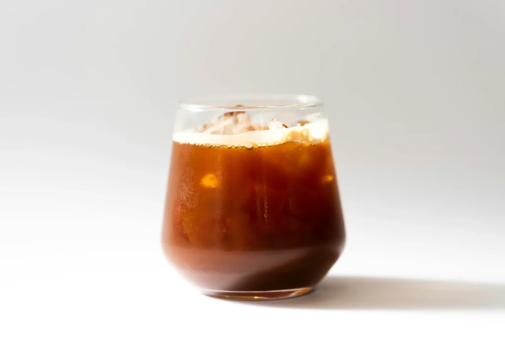 Glas Cold Brew mit Eiswürfeln vor hellem Hintergrund